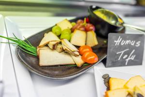 a plate of food with cheese and vegetables on a table at Bergresort Gerlitzen by ALPS RESORTS in Treffen