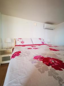 - une chambre avec un lit orné de fleurs rouges dans l'établissement Monteforte Home - Ruggero, à Catane
