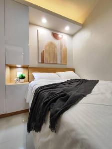 a bedroom with a bed with a black blanket on it at Scandi-Style & Organic condo Shore 3 MOA in Manila