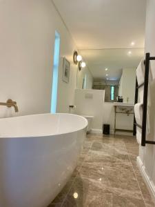 uma casa de banho com uma grande banheira branca num quarto em Mountain Cottages at Haskell Vineyard em Stellenbosch