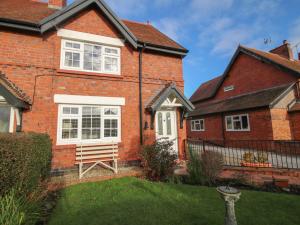 una casa de ladrillo con un banco de madera en el patio en 8 New Houses, en Wrexham