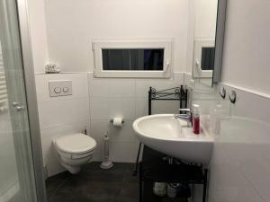 een witte badkamer met een toilet en een wastafel bij 2-Zimmer Wohnung mit Gym/Office in Frankfurt am Main