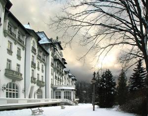 a large white building with snow on the ground at Hotel Palace in Sinaia