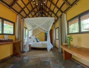 Maramba River Lodge في ليفينغستون: غرفة نوم بسرير مع مظلة
