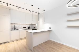 una cocina con armarios blancos y una isla blanca en Hygge Sand Apartment en Vilna