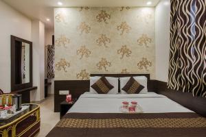 a bedroom with a bed and a wall with wallpaper at Hotel Joy in Jaipur