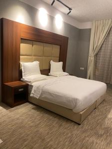 a bedroom with a large bed with a wooden headboard at أجنحة هدوء الفندقية in Riyadh