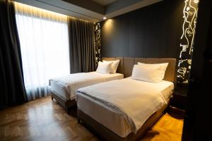 a bedroom with two beds and a window at Arka Art Hotel in Tirana