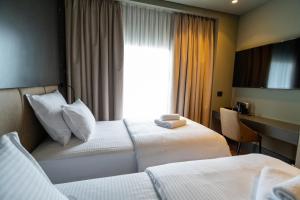 a hotel room with two beds and a window at Arka Art Hotel in Tirana