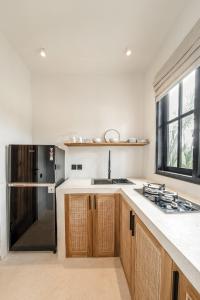 uma cozinha com armários de madeira e um frigorífico preto em Sarang Apartments by EVDEkimi Ubud em Ubud