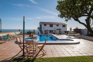 a swimming pool with chairs and a table and a house at Casa rural junto al mar in Benalmádena