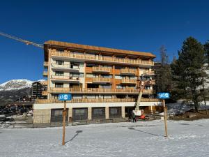 a building in the snow with two signs in front of it at Appartement sur piste à Praloup in Uvernet-Fours
