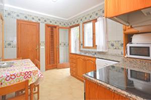 a kitchen with wooden cabinets and a table with a microwave at Boreal House in Alcudia