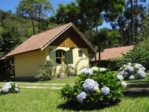 a small house with flowers in the yard at Pousada Sítio das Astrapéias in Visconde De Maua