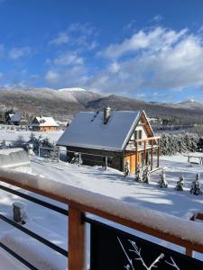 una casa con nieve en el techo en Kruszyna - domek z widokiem na połoniny, en Smerek