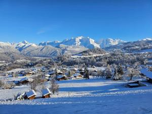 wioska pokryta śniegiem z górami w tle w obiekcie Les Balcons du Mont-Blanc : Appartement centre village w mieście Cordon
