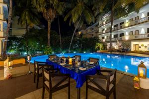 a dining table in front of a swimming pool at night at Sterling Goa Varca in Varca