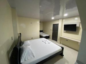 um quarto com uma cama branca e uma televisão em Hotel Villa Grant em Aguachica