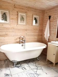 a bathroom with a white tub in a wooden wall at Shepherd's Hut at Cefn Tilla Court in Usk