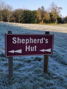 a brown sign with two arrows on a field at Shepherd's Hut at Cefn Tilla Court in Usk