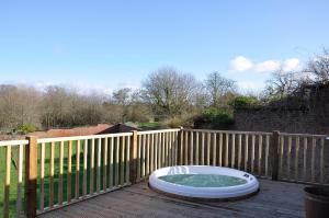 un bain à remous installé au-dessus d'une terrasse en bois dans l'établissement Shepherd's Hut at Cefn Tilla Court, à Usk