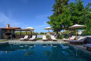 a swimming pool with lounge chairs and umbrellas next to at Platanias Villa Spyros in Platanes