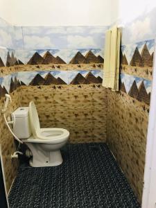 a bathroom with a toilet and a mural of pyramids at Walkers hostel in Trincomalee