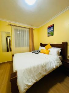 - une chambre avec un grand lit blanc aux murs jaunes dans l'établissement Lovely 2 Bedroom Apartment in Ongata Rongai, à Langata Rongai