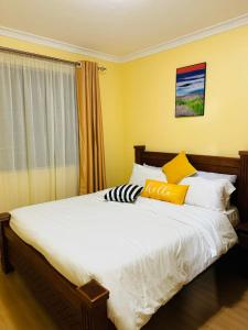 - une chambre avec un grand lit aux murs jaunes dans l'établissement Lovely 2 Bedroom Apartment in Ongata Rongai, à Langata Rongai