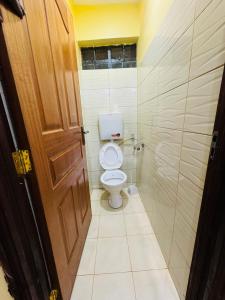 La salle de bains est pourvue de toilettes et d'une porte en bois. dans l'établissement Lovely 2 Bedroom Apartment in Ongata Rongai, à Langata Rongai