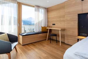 een slaapkamer met een bureau en een bed met een raam bij Granpanorama Hotel StephansHof in Villandro +71 foto's