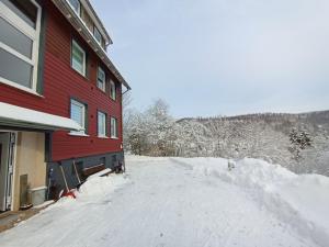 a snow covered road next to a red building at Haus Christoffel Wieda in Wieda