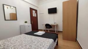 a bedroom with a bed and a desk and a television at FlipHouse Rooms Pensión in Bilbao