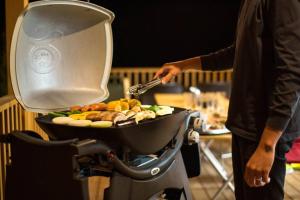 a person is cooking food in a grill at 山が見える貸切コテージ「WIND+HORN」 