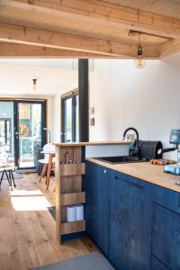 an open kitchen with blue cabinets and a sink at Undine - Wunderschönes Tiny Hausboot in Hamburg