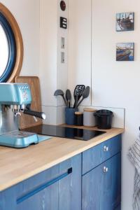 a kitchen with blue cabinets and a counter top at Undine - Wunderschönes Tiny Hausboot in Hamburg