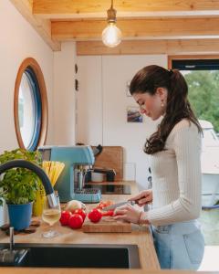 una mujer parada en una cocina cortando tomates en Undine - Wunderschönes Tiny Hausboot en Hamburgo