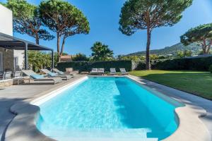 a swimming pool with chaise lounge chairs next to a house at Domaine Villas Mandarine Private Pools & Spa in Calvi