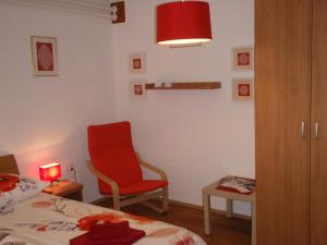 a bedroom with a red chair and a bed and a table at Sobe Vera in Bovec