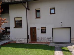 una casa blanca con dos puertas de garaje y un patio de césped en Sobe Vera en Bovec