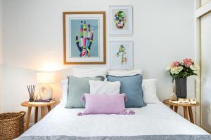 1 dormitorio con cama blanca y almohada rosa en Cottage at 22, en Mount Gambier