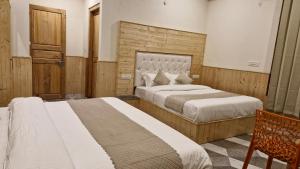 a bedroom with two beds and a wooden wall at Red House Cafe & Inn in Jibhi