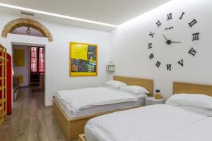 dwa łóżka w pokoju z zegarem na ścianie w obiekcie I Della w Mediolanie