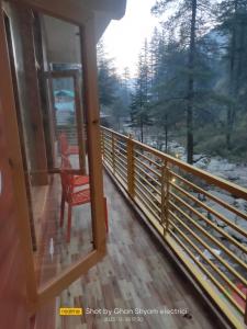 uma vista a partir da varanda de um quarto com uma cadeira em Red House Cafe & Inn em Jibhi