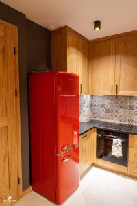 a red refrigerator in a kitchen with wooden cabinets at Zarębisko - noclegi całoroczne in Zwierzyniec