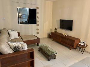 uma sala de estar com um sofá e uma televisão de ecrã plano em Casa Recanto dos Guaiamuns - Carneiros PE em Sirinhaém