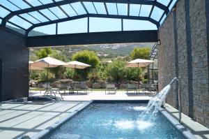 una piscina con una fuente, mesas y sombrillas en Domaine Villas Mandarine Private Pools & Spa en Calvi