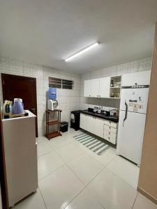 a kitchen with white appliances and white tile walls at Casa Recanto dos Guaiamuns - Carneiros PE in Sirinhaém