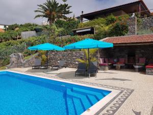 a pool with umbrellas and chairs next to a house at Lucky Lemons - Boutique Houses Madeira (Studio) in Calheta