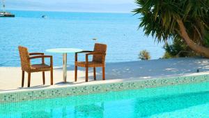 2 sillas y una mesa junto a la piscina en Porto Evia Boutique Hotel en Amarynthos